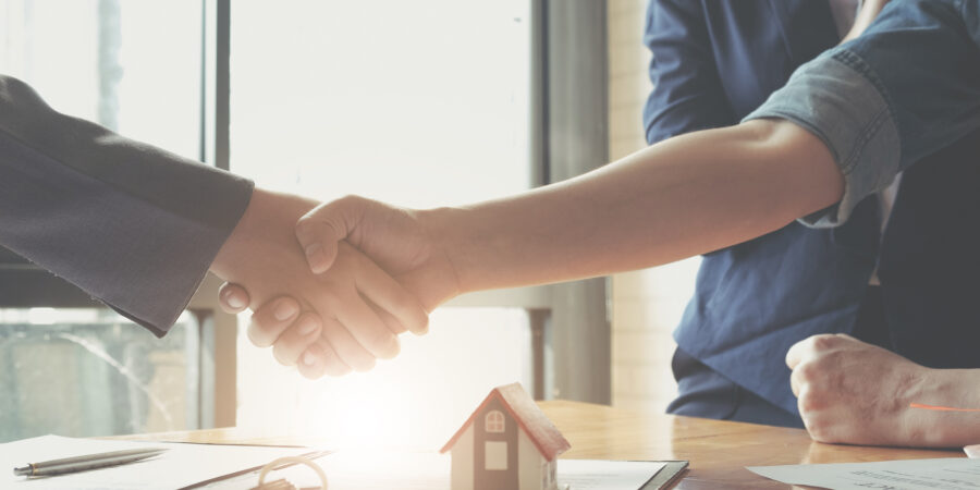 couple buying a home and shaking hands with a real estate agent